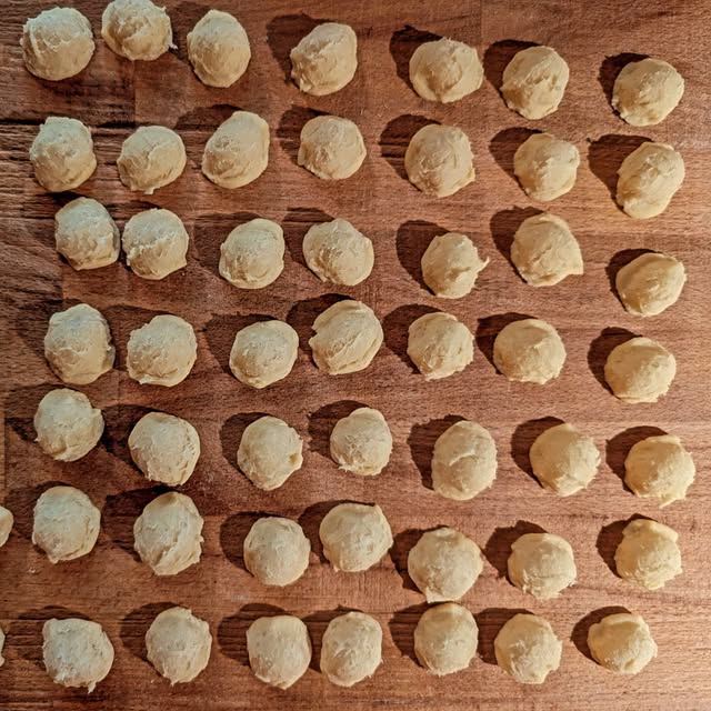 Rows of hand-rolled gnocchi dough on a wooden board